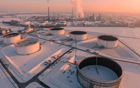 Industrial tanks in a snowy landscape at sunrise